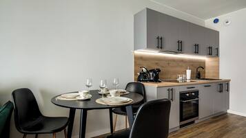 A modern kitchen with grey cabinets, a wooden countertop, and a dining area with black chairs and a round table set for four.