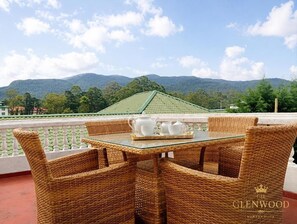 A wicker table with chairs on a balcony overlooking a mountainous landscape. - Glenwood Nuwara Eliya (Nuwara Eliya)