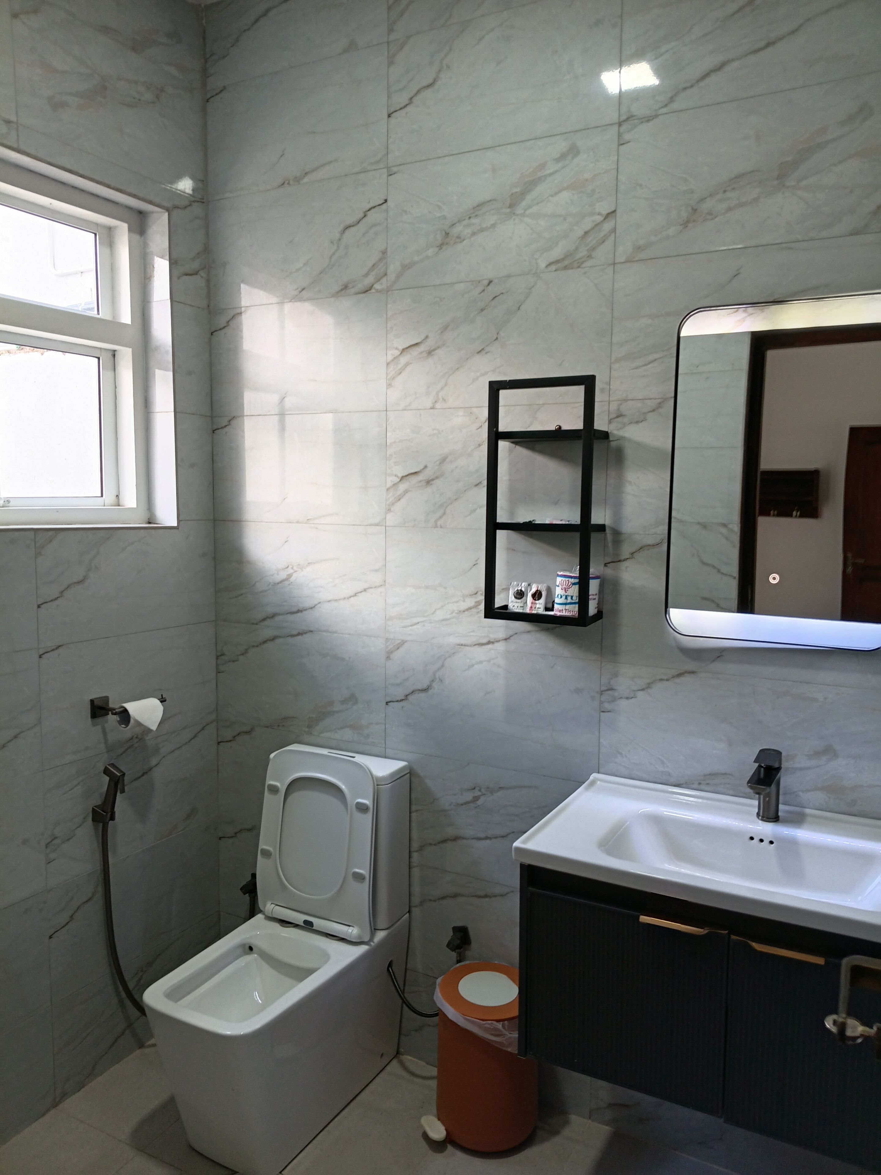 Un baño con inodoro, lavabo, espejo y ventana.