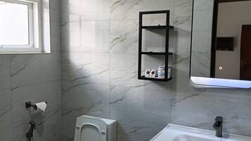 Un baño con inodoro, lavabo, espejo y ventana.