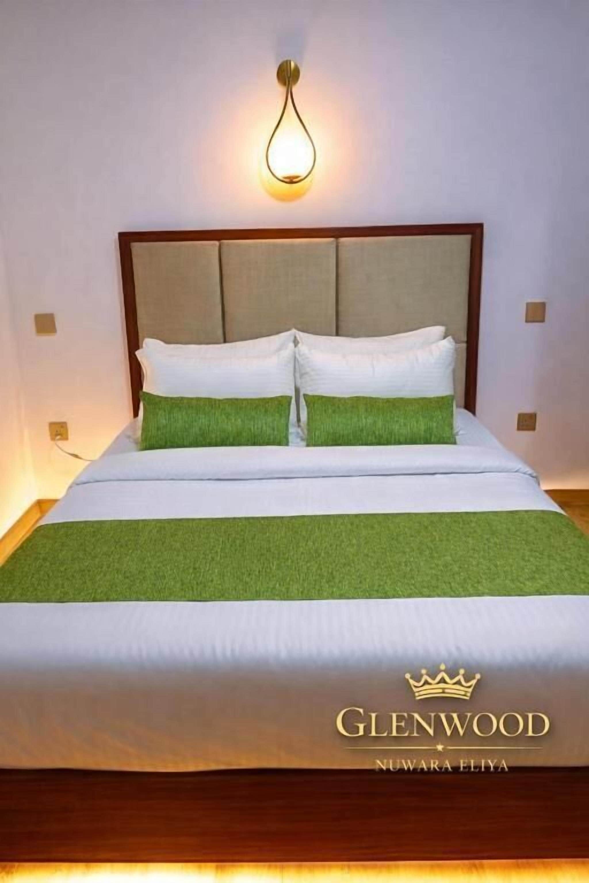 A hotel room with a bed, a headboard, and a wall-mounted light fixture.