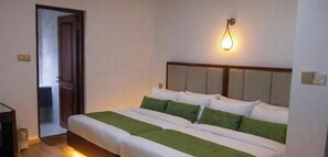 Une chambre d’hôtel comprenant un lit, une table de chevet, un luminaire fixé au mur et une porte donnant sur une autre pièce.