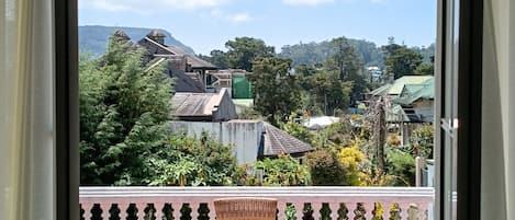 Un balcón con mobiliario de mimbre y vista a una zona residencial con casas y árboles.