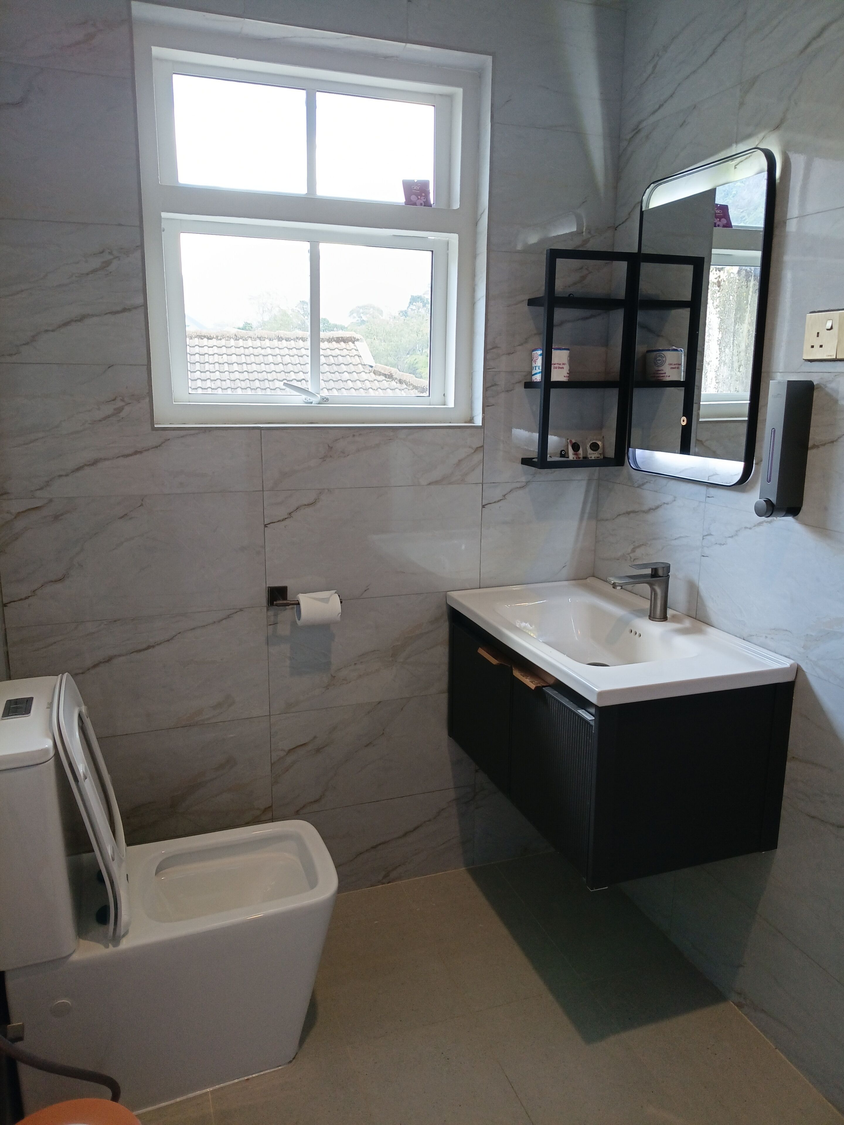 A bathroom with a toilet, a sink, a bathtub, a window, and a mirror.