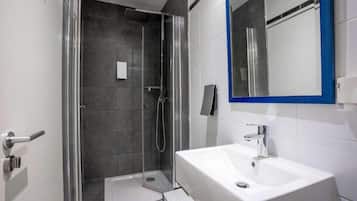 Un baño moderno con ducha de vidrio, lavamanos blanco y espejo con marco azul.