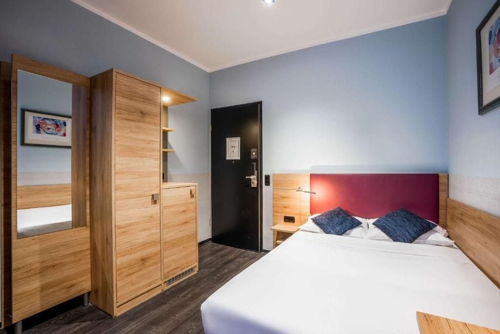 Ein Hotelzimmer mit Bett, Kleiderschrank, Tür und einer Wandlampe.