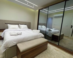 Un dormitorio moderno con una cama grande, un banco, un vestidor y un armario con espejo.