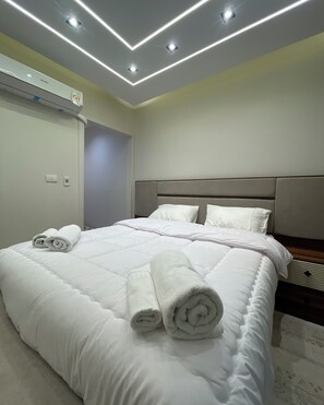 Habitación de hotel con una cama grande, cabecera e iluminación empotrada en el techo.