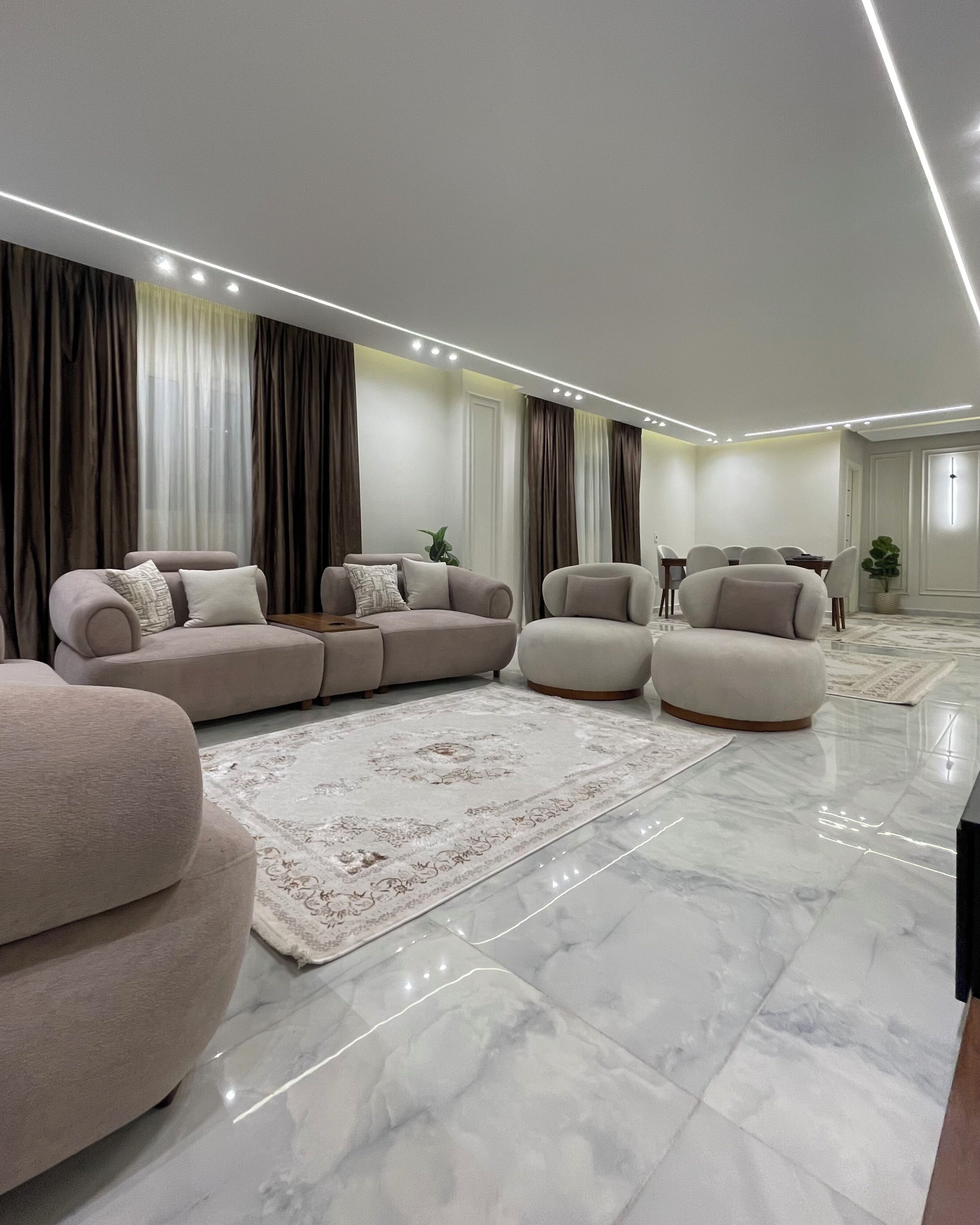 Una sala de estar moderna con un sofá modular, sillones, una mesa de centro y un tapete estampado.