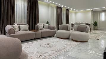 Una sala de estar moderna con un sofá modular, sillones, una mesa de centro y un tapete estampado.