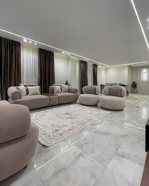Una sala de estar moderna con un sofá modular, sillones, una mesa de centro y un tapete estampado.