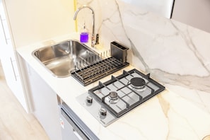 A kitchen with a stainless steel sink, a black stove with a gas range, and a marble countertop. - StayShort - Minutes to Downtown - Sleek Meydan Apartment with Balcony - Sleeps 4 (Dubai)