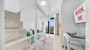 Un interior moderno con escalera, un sofá verde, un comedor y vistas al exterior.