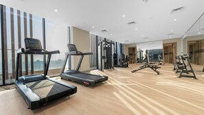 Un gimnasio con cintas de correr, máquinas de pesas y un espejo grande.
