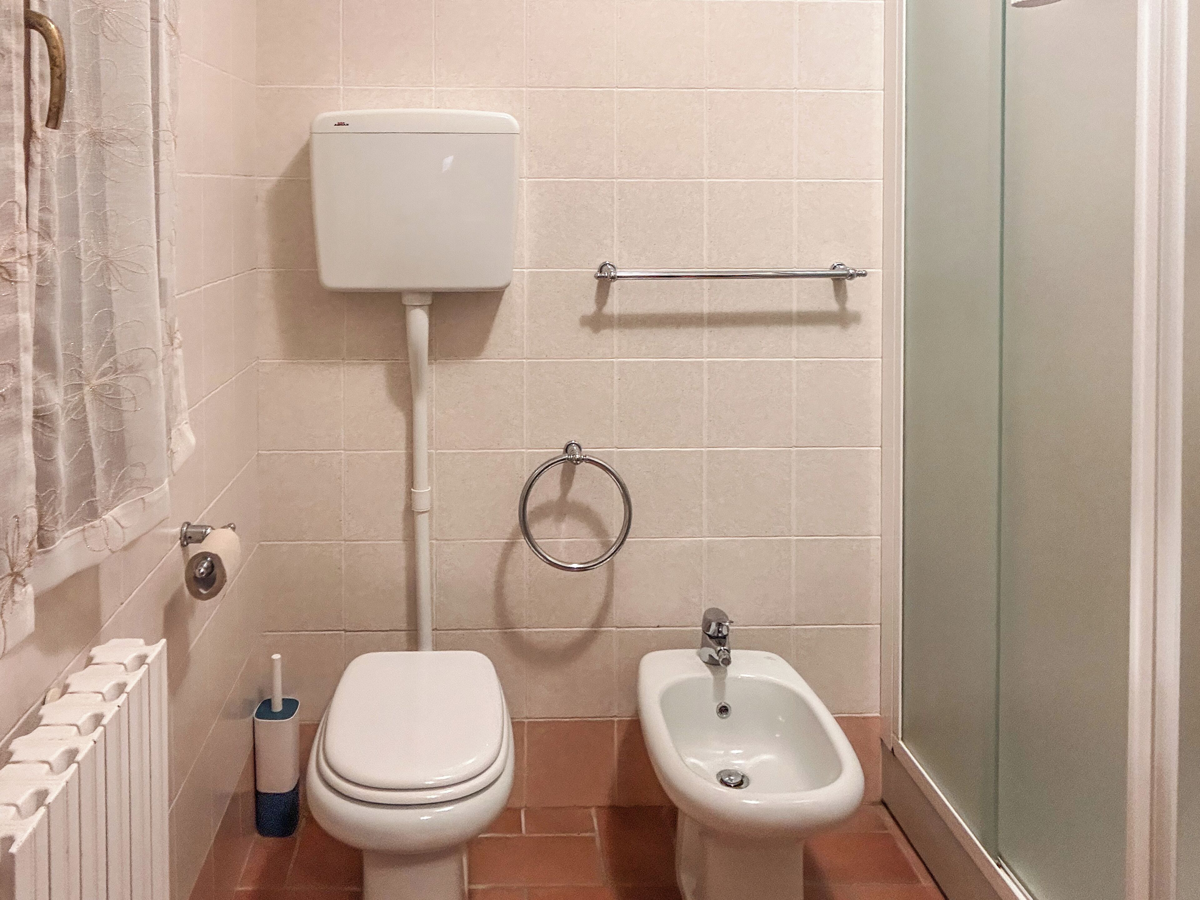 A bathroom with a toilet, bidet, and a towel rack.