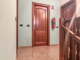 A hallway with a wooden door labeled '2', a fire extinguisher, and a staircase.