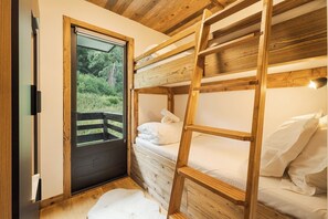 A wooden bunk bed room with a door leading to an outdoor area. - Avenieres - Family-Friendly Getaway | 4 Guests | Megève | Balcony (Megève)