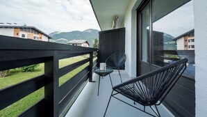 En balkon med udsigt til bjerge, en stol og et lille bord.