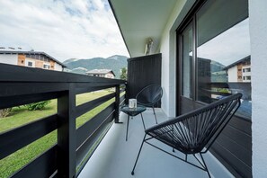 A balcony with a view of mountains, a chair, and a small table. - Avenieres - Family-Friendly Getaway | 4 Guests | Megève | Balcony (Megève)