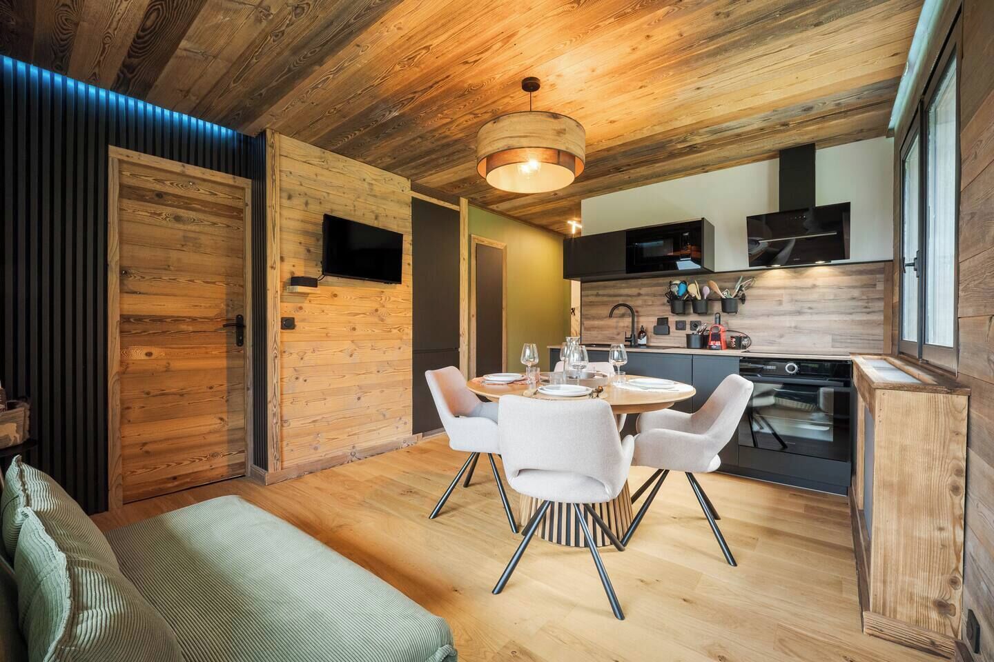 A modern kitchen with wooden accents, a dining area with a round table and chairs, and a cozy seating area with a sofa.