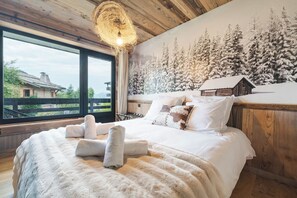 A bedroom with a large bed, a wooden headboard, a view of a snowy landscape, and a rustic decor theme. - Avenieres - Family-Friendly Getaway | 4 Guests | Megève | Balcony (Megève)