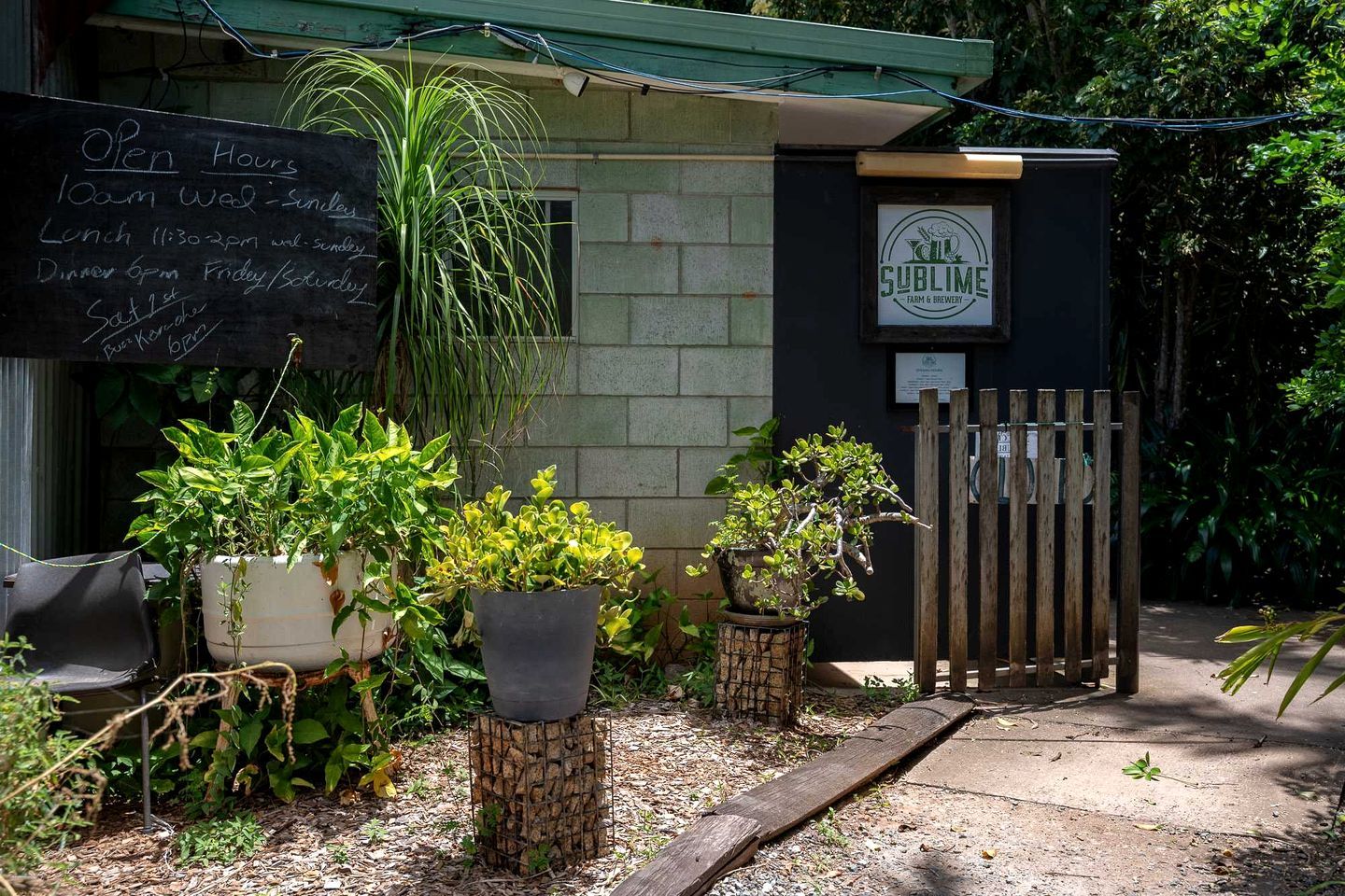 A building with a signboard listing open hours and a logo for 'Sublime Farm & Brewery'.