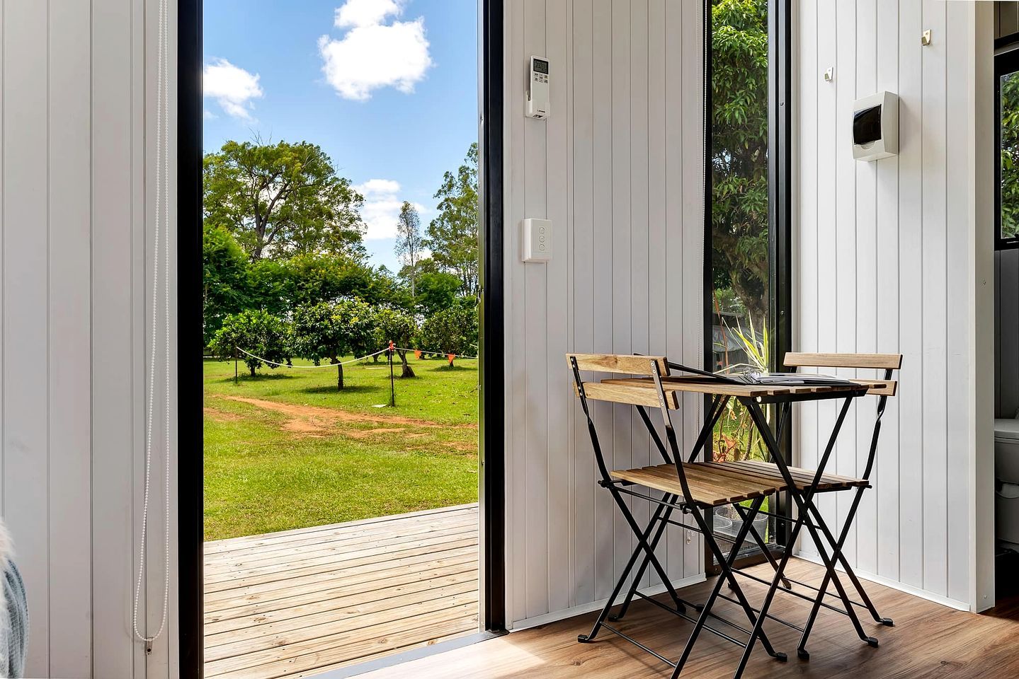 A room with a sliding glass door leading to an outdoor area with a table and chairs.