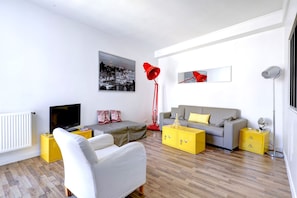 A modern living room with a sofa, armchair, and a television. - Chic 1BR by Louvre & Palais Royal (Paris)