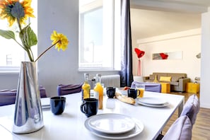 A modern dining area with a table set for breakfast, including plates, cups, and a vase with flowers. - Chic 1BR by Louvre & Palais Royal (Paris)