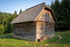 Una cabaña rústica de madera con base de piedra, una ventana y una chimenea.