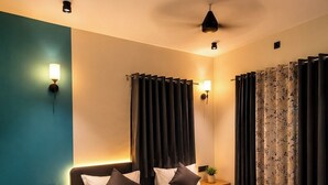 A modern hotel room with a large bed, two bedside tables, a nightstand, and a wall-mounted lamp.