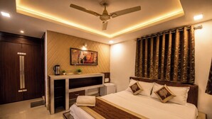 A bedroom with a bed, a desk, a ceiling fan, and a wall-mounted TV.