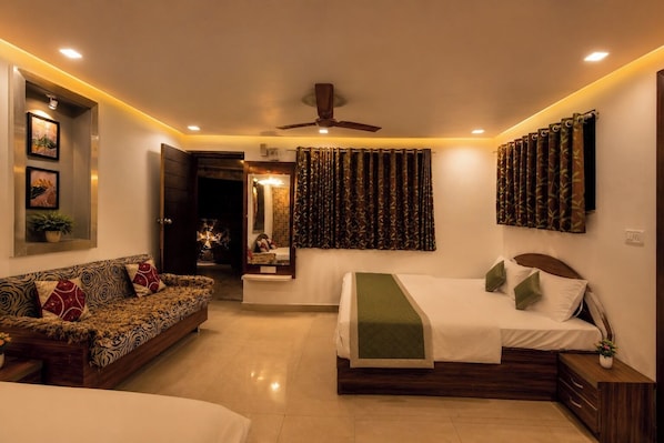 A modern bedroom with a bed, a sofa, a ceiling fan, and a mirror.