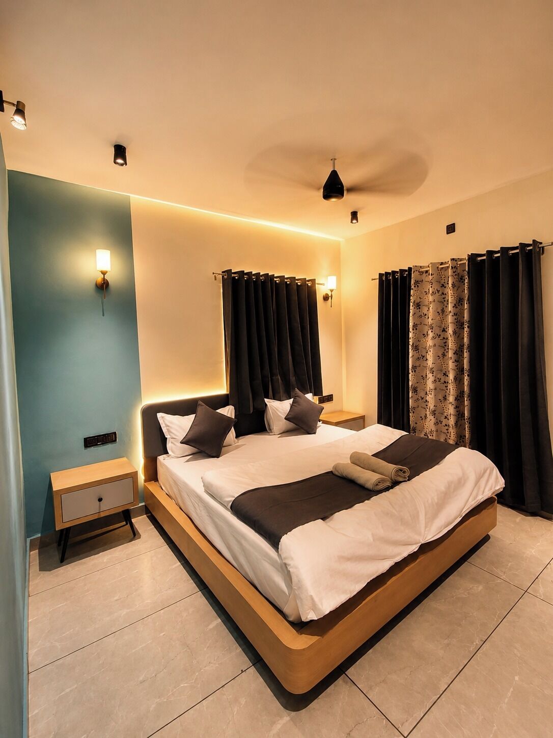 Un dormitorio moderno con una cama grande, mesitas de noche y cortinas.