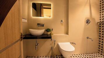 A bathroom with a white sink, a mirror, a shower, and a toilet.