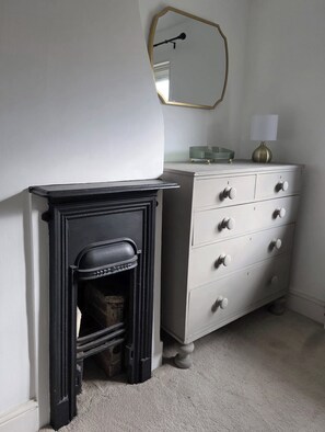 A room with a fireplace, a dresser, and a mirror on the wall. - A cosy Suffolk cottage in Honington. (Honington)