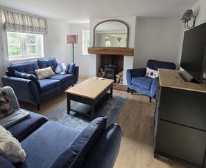 A living room with a fireplace, two sofas, a coffee table, and a television. - A cosy Suffolk cottage in Honington. (Honington)