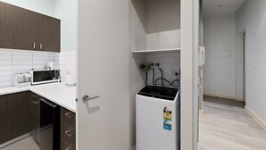 Una cocina moderna con microondas integrado, cafetera y refrigerador pequeño.