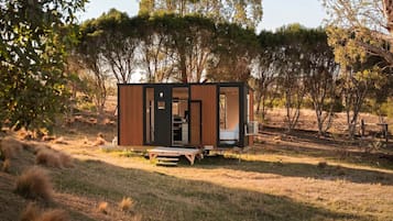 Une petite cabane à un seul étage, dotée d’une porte, d’une fenêtre et d’un petit porche.