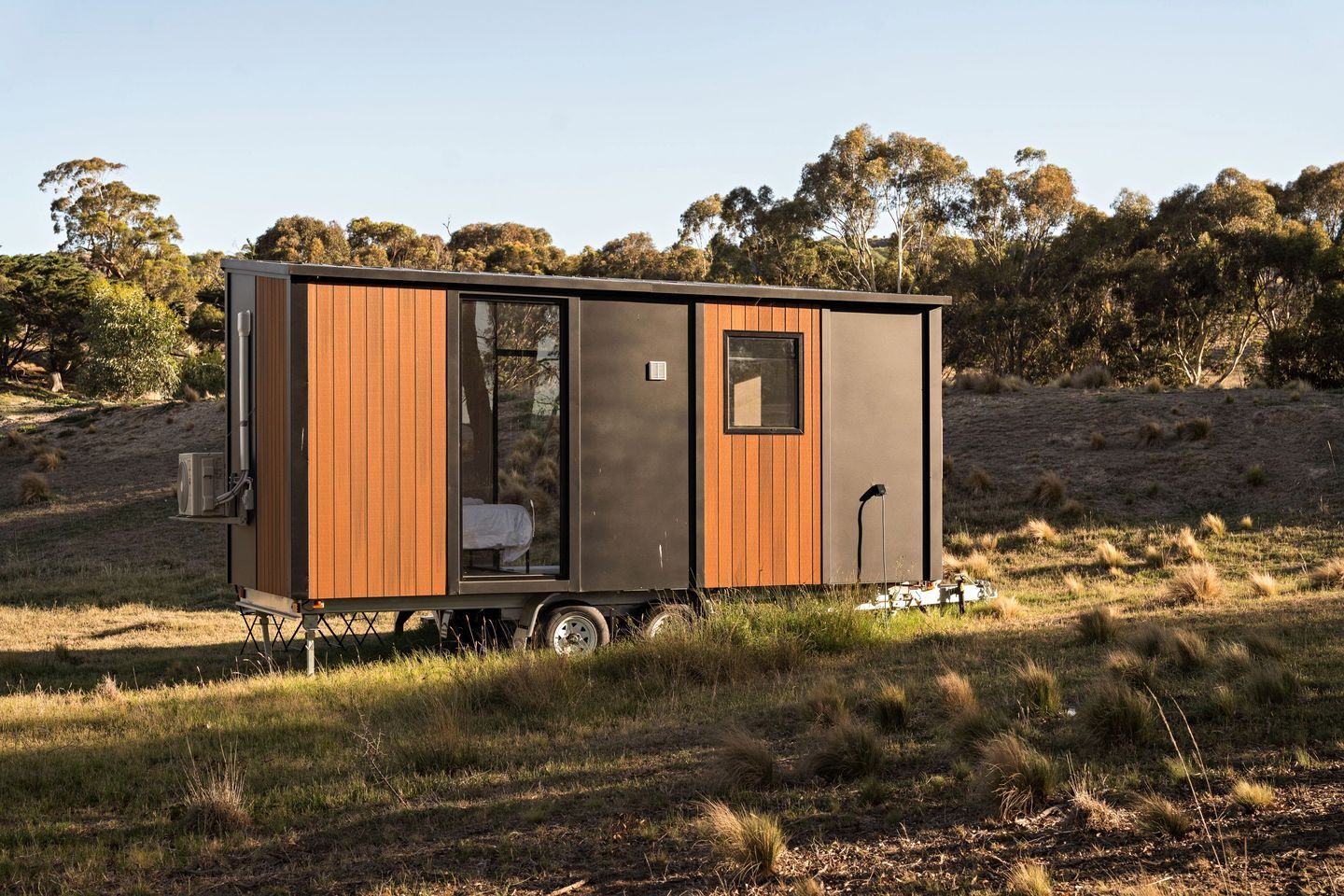 A mobile home with a sleeping area, a small window, and a kitchenette.