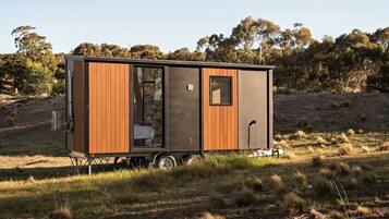 A mobile home with a sleeping area, a small window, and a kitchenette.