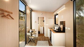 Een moderne, compacte kamer met een bed, een eettafeltje en een kitchenette.