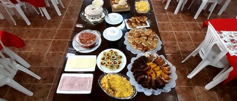 A buffet setup with various food items and white plastic chairs arranged around tables.