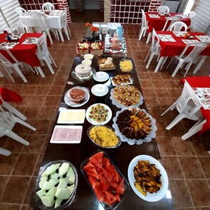 A buffet setup with various food items and white plastic chairs arranged around tables.