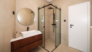 A modern bathroom with a glass-enclosed shower, a round mirror, and a wooden vanity. - Villa Anamaria Zadarvillas (Zadar)