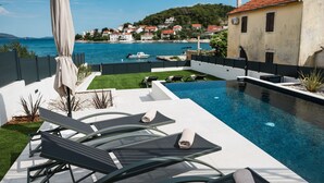 A swimming pool with lounge chairs and a view of a coastal town. - Villa Anamaria Zadarvillas (Zadar)