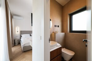 Ein modernes Hotelzimmer mit einem Bett, Nachttisch und einem Badezimmer mit Toilette und Waschbecken.