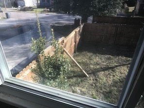 A window view of a fenced yard with a wooden fence, a small plant, and a metal ladder leaning against the fence. - 3 bedroom central in Chattanooga (Chattanooga)