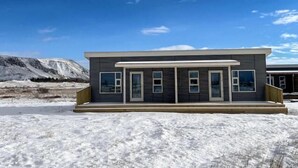 A modern two-story building with a flat roof, large windows, and a wooden deck. - Ferjukot Apartments (Sveitarfélagið Ölfus)