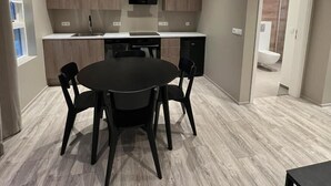 A modern kitchen with a central island, built-in cabinets, and a dining area with a round table and chairs. - Ferjukot Apartments (Sveitarfélagið Ölfus)